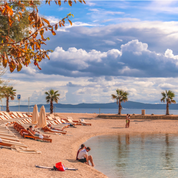 people sitting on sand at Kasjuni Beach