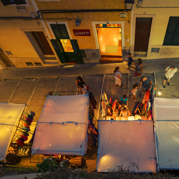 people shopping at stalls at night market in menorca