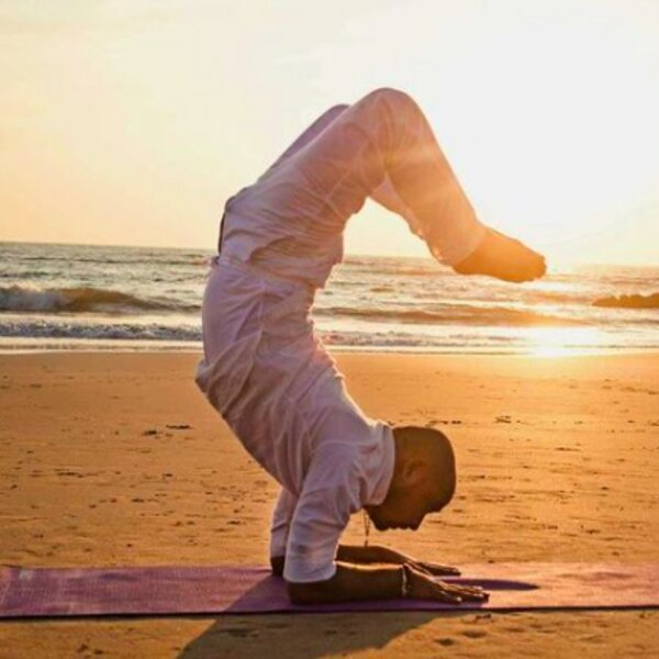 man doing yoga on a beach in goa