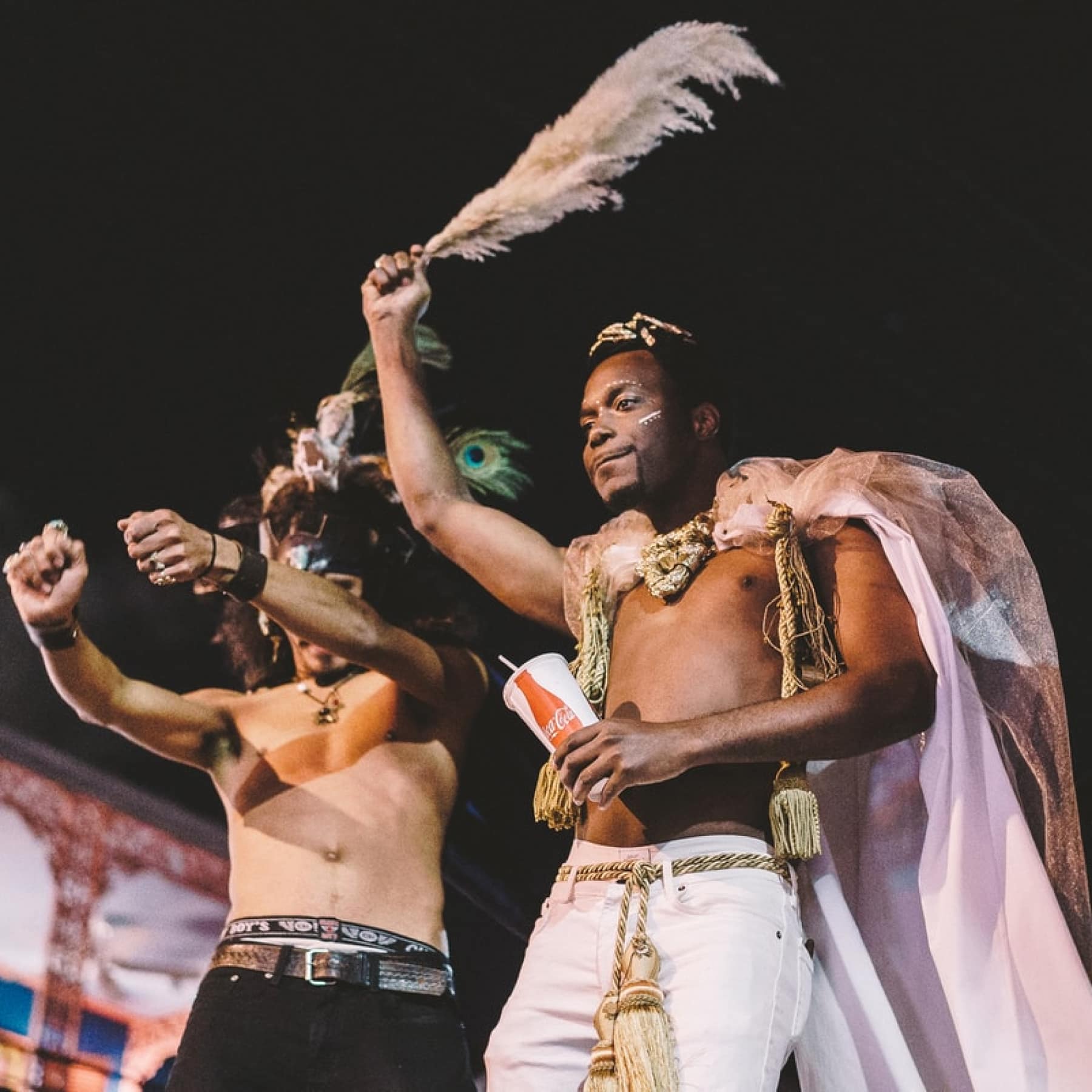 Two men celebrating in the streets of New Orleans with large feathers waving