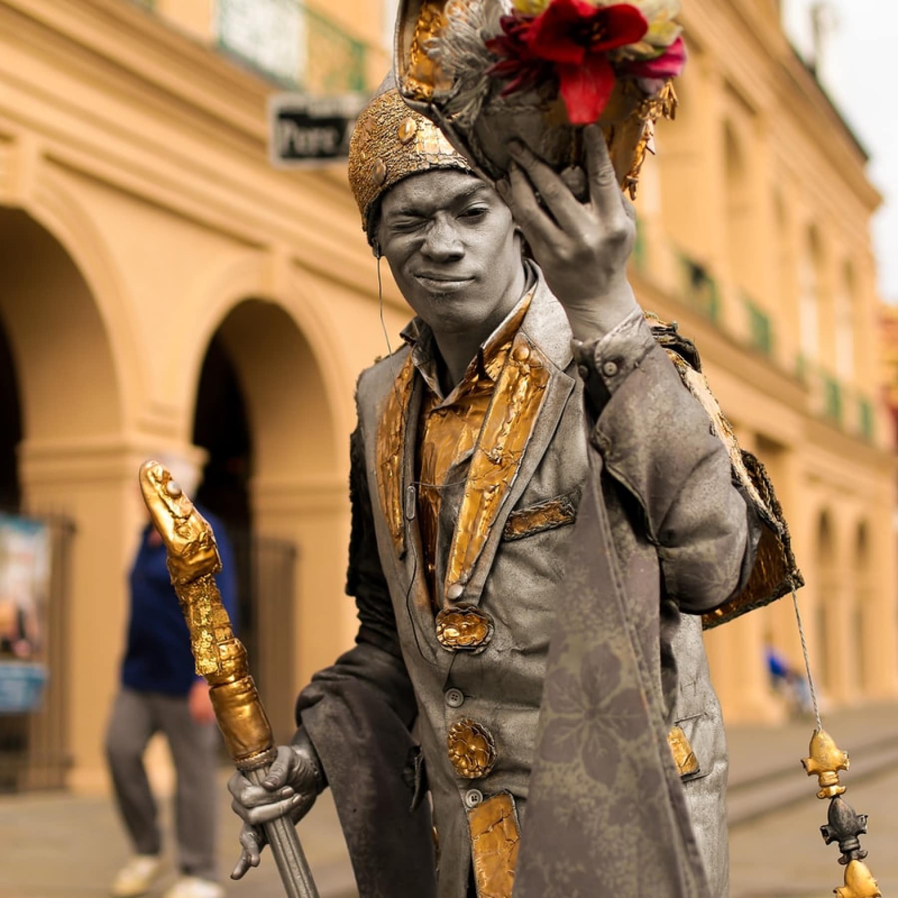 A man painted in bronze, winking at a camera