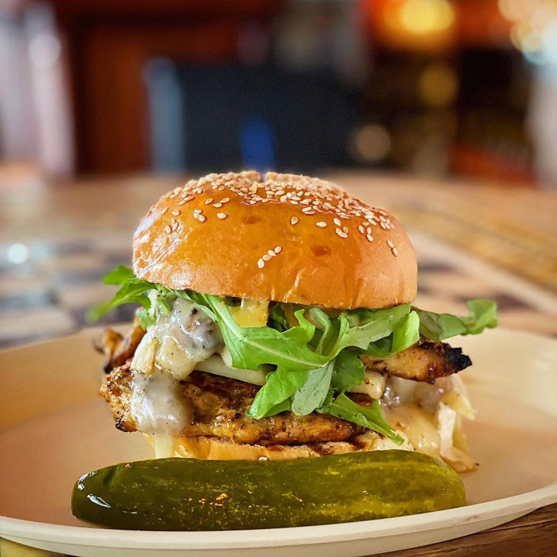 A chicken burger with pickle on the side