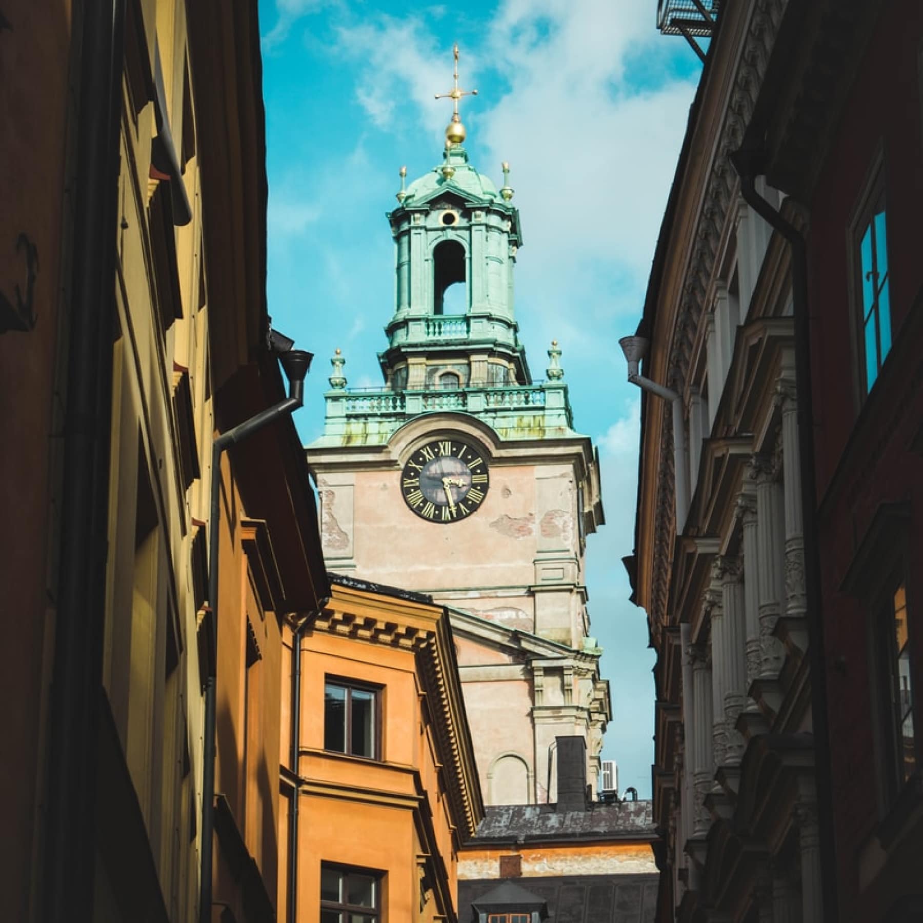 A quaint street in Gamla Stan, looking up to the skyline and a clock and church bell