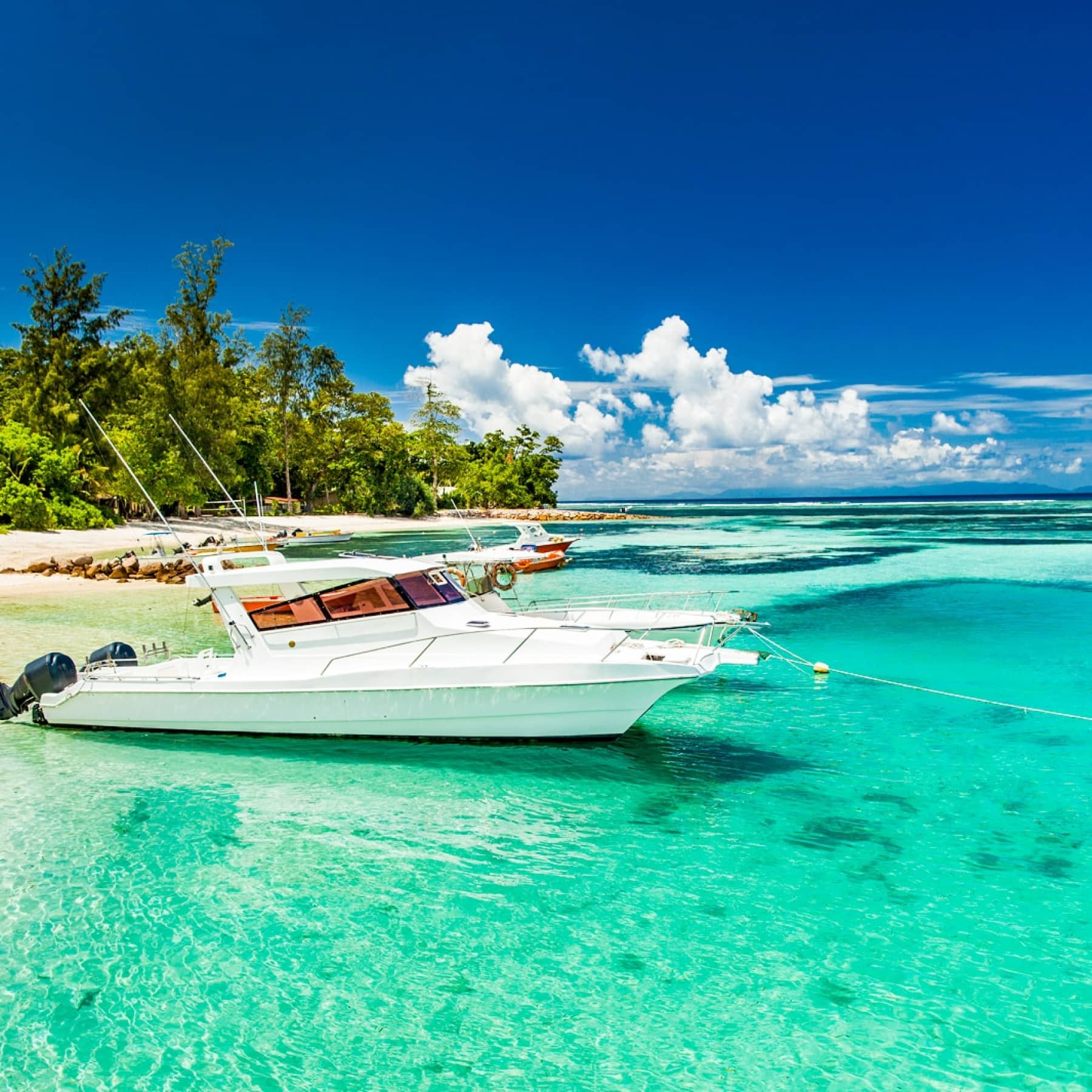 Boats sit on the water of the Seychelles before adventuring
