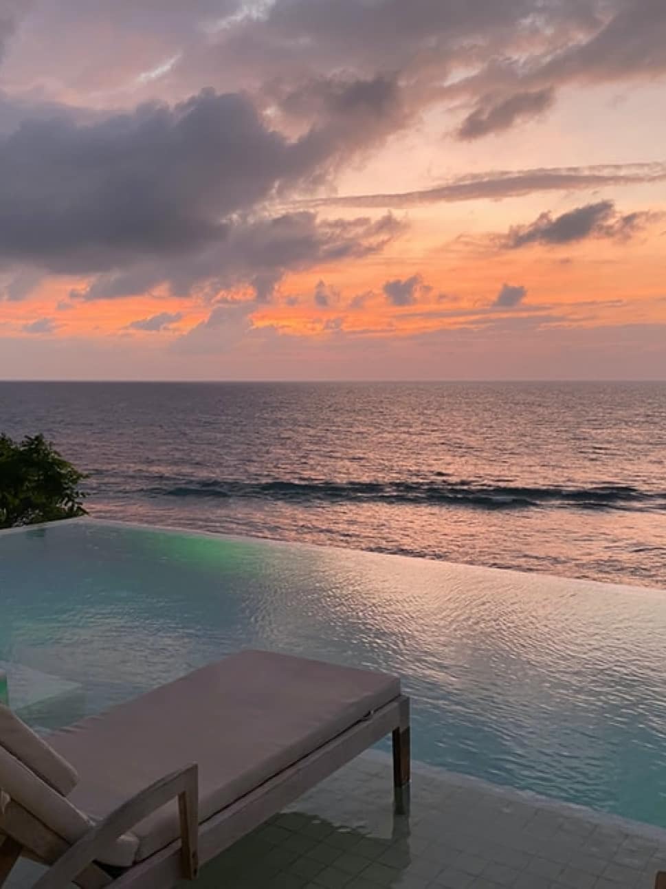 Beautiful sunset by an infinity pool with deck chairs in front of it